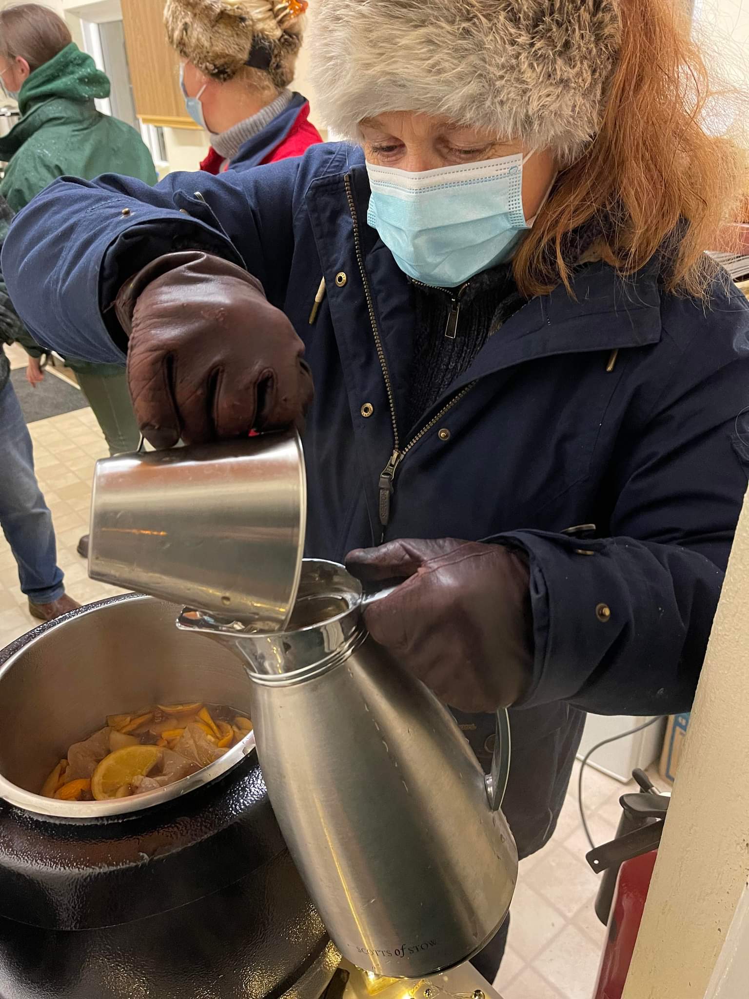 a woman in hat mask and gloves serving drinks